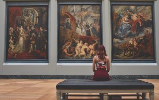 Blog image of woman sat in art museum for How Hiring Fine Art Shippers Secures Your Art's Future