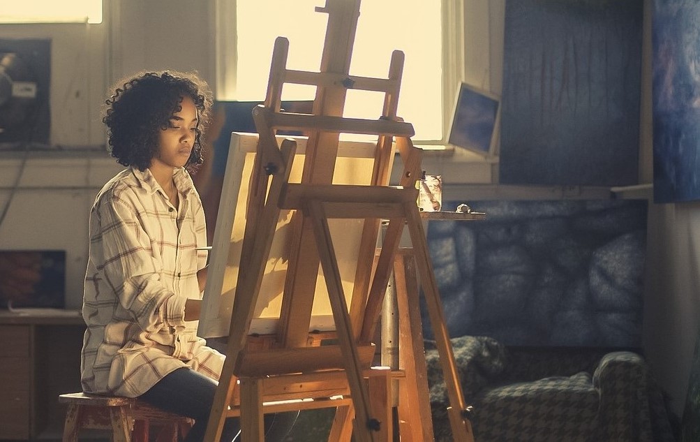 an artist sits in front of her work in this image