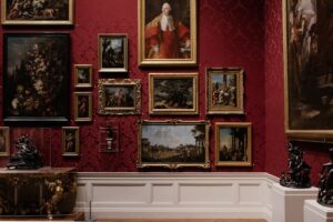 Image of a red wall with fine artworks hung on it for the blog Why Fine Art Shippers Are Essential For Art Collectors 