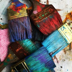 Image of 4 paint brushes covered in paint